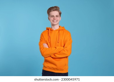 Portrait of smiling teenage boy on light blue background - Shutterstock ID 2300045971