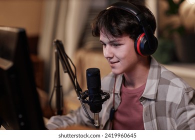 Portrait of smiling teenage boy playing video games online on PC computer with wireless headset and speaking to microphone - Powered by Shutterstock