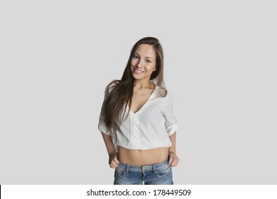 Portrait Of Smiling Teenage Girl In Crop Top Posing Against Gray Background