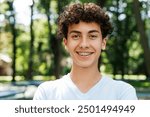 Portrait of smiling teenager boy with braces looking at camera posing in the park. Lifestyle emotions concept