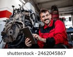 Portrait of smiling tractor mechanic holding tablet computer and standing by the engine.