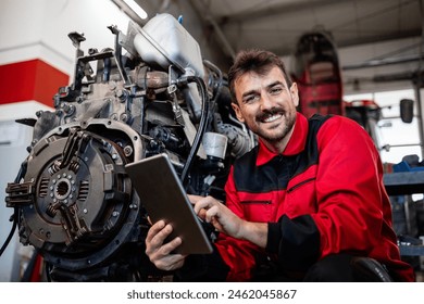 Portrait of smiling tractor mechanic holding tablet computer and standing by the engine. - Powered by Shutterstock