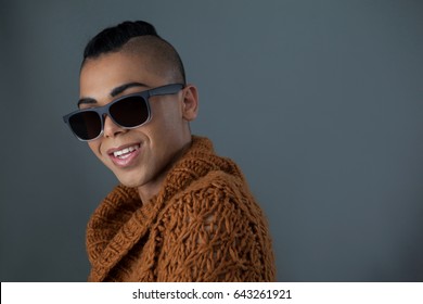 Portrait of smiling transgender woman wearing sunglasses against gray background