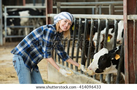 Portrait of smiling veterinary technician feeding cows in farm