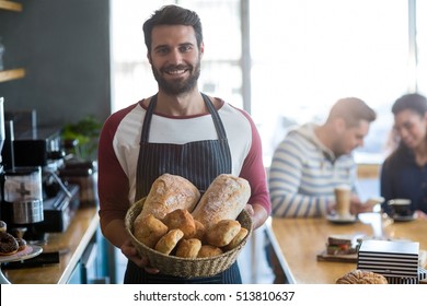 Portrait of smiling waiter holding a basket of bread in cafÃ© - Powered by Shutterstock