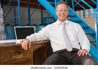 Portrait of smiling warehouse manager with computer at warehouse
