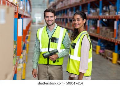 Portrait Of Smiling Warehouse Workers Scanning Box In Warehouse