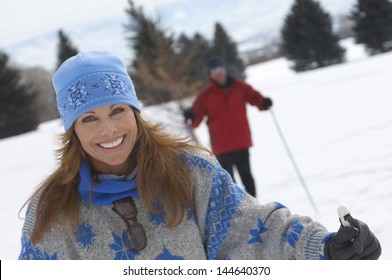Portrait Of Smiling Woman Cross Country Skiing With Blurred Man In The Background