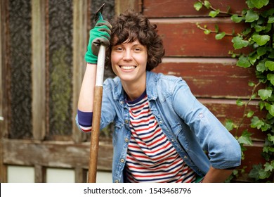 Portrait Of Smiling Woman With Garden Tool, Posing By Shed