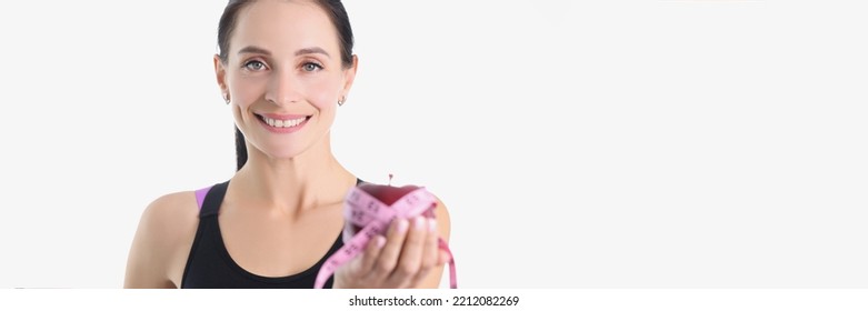 Portrait Of A Smiling Woman Holding An Apple And Centimeter. Diet Proper Nutrition And Sport Concept