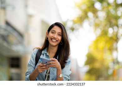 Portrait smiling woman holding mobile phone outdoors 