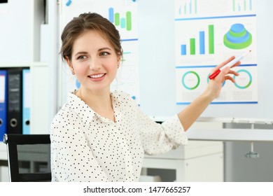 Portrait Of Smiling Woman Indicating Financial Statements To Board Directors. Young Businesswoman At Seminar. Company And Business Meeting Concept. Blurred Background