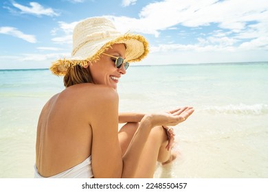 Portrait of smiling woman on sandy tropical beach wearing white bikini and summer hat. Face of beautiful young girl enjoying seaside. Copy space. Island vibes. 
 - Powered by Shutterstock