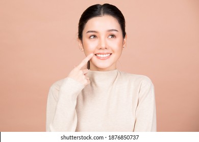 Portrait Of Smiling Woman Pointing At Her Nice Teeth And Mouth Isolated On Brown Background