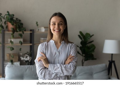 Portrait of smiling woman satisfied client of interior design studio. Confident young female homeowner stand at modern living room of new purchased renovated flat look at camera holding arms crossed - Shutterstock ID 1916665517