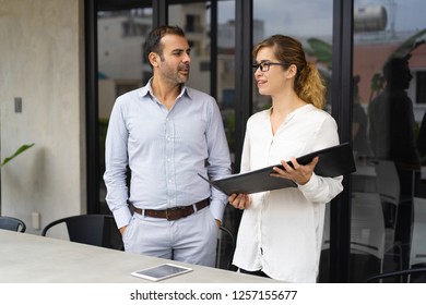 Portrait of smiling woman showing project to her executive in papers. Caucasian businessman and businesswoman talking in boardroom. Planning concept