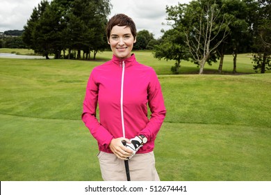 Portrait of smiling woman standing with golf club in golf course