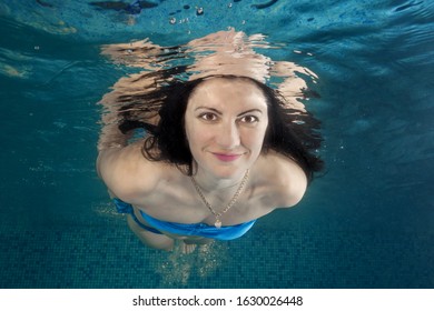 Portrait Of Smiling Woman In A Swiming Suit Dives Underwater In The Swimming Pool