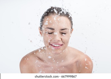Portrait of smiling woman taking shower isolated on white