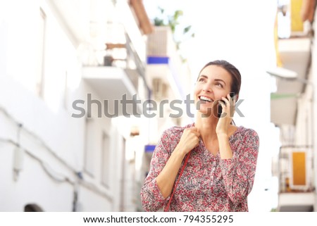 Portrait of smiling woman talking on mobile phone outside on street