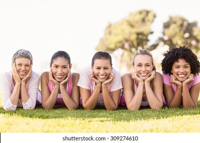 Portrait of smiling women lying in a row and wearing pink for breast cancer in parkland