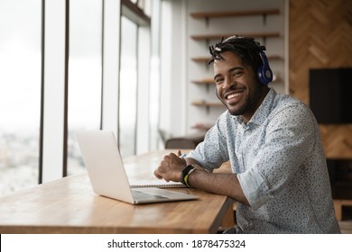 Portrait of smiling young African American man in headphones talk on video call on laptop. Happy millennial biracial male in earphones have webcam digital virtual conference on computer online. - Powered by Shutterstock