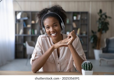 Portrait of smiling young African American woman in earphones look at camera have webcam digital virtual event. Happy ethnic female in headphones talk speak on video call. Communication concept.