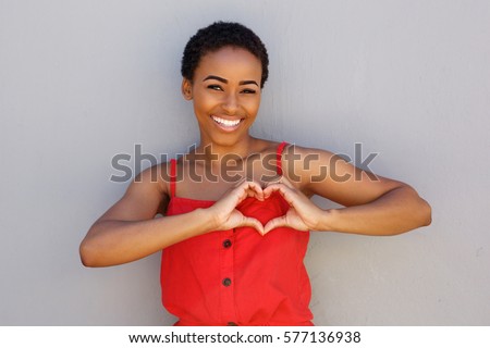 Portrait of smiling young african american woman with heart shape hand sign 