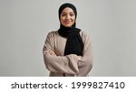 Portrait of smiling young arabian girl in black hijab looking at camera on light background, widescreen. Beautiful muslim lady
