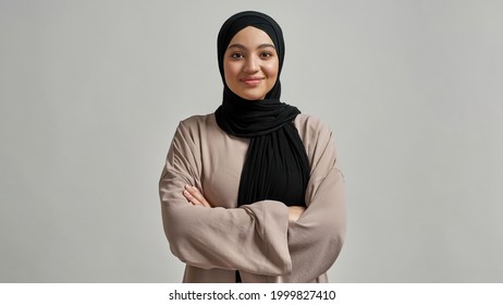 Portrait of smiling young arabian girl in black hijab looking at camera on light background, widescreen. Beautiful muslim lady