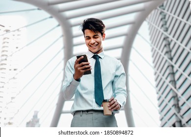 Portrait Of A Smiling Young Asian Businessman Using Mobile Phone In The City 