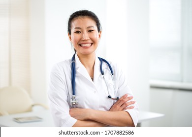 Portrait Of Smiling Young Asian Female Doctor In A Background For Your Text.