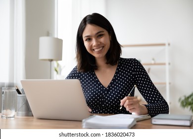 Portrait of smiling young asian female student study online or take web course training on computer. Happy Vietnamese woman make notes work on laptop from home office. Distant education concept.