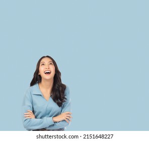 Portrait smiling young asian woman with crossed arms Happy asia girl posing with crossed arms and looking at above stand over light blue background and copy space Confident female get happy and  relax