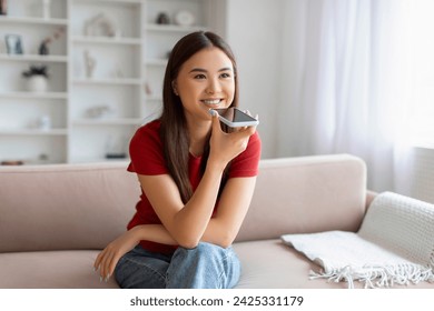 Portrait Of Smiling Young Asian Woman Recording Voice Message On Smartphone While Resting At Home, Happy Korean Female Using Virtual Assistant On Mobile Phone, Enjoying Modern Technologies - Powered by Shutterstock