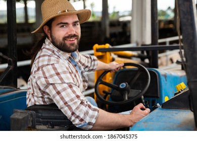 Portrait Of Smiling Young Bearded Farmer Sitting On Small Farm Tractor..
