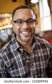 Portrait Of Smiling Young Black Man In The Interior Of Coffee Shop.