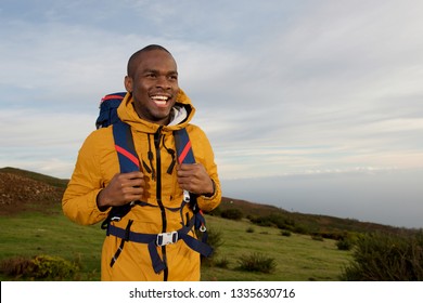 Portrait Of Smiling Young Black Man With Backpack Walking In Nature