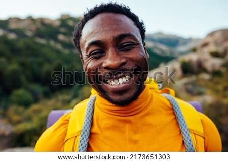 A portrait of a smiling young black mountain hiker with full gear