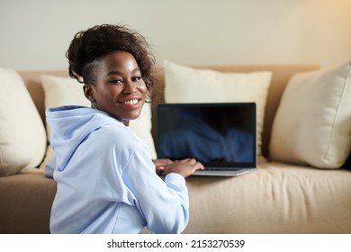 Portrait Of Smiling Young Black Woman Working On Laptop And Turning Back To Camera