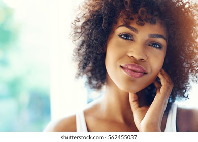 Portrait Of Smiling Young Black Woman In Sunshine With Chin On Hand And Copy Space