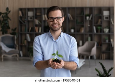 Portrait of smiling young businessman hold soil and small plant launch startup project or activity. Happy millennial male employee or CEO with seedling sprout in hands. Growth, development concept. - Powered by Shutterstock