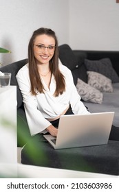 Portrait Of Smiling Young Businesswoman Working On Laptop At Home Office Wearing White Shirt And Black Track Suit.