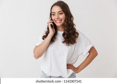 Portrait Of A Smiling Young Casual Brunette Woman Talking On Mobile Phone Isolated Over White Background