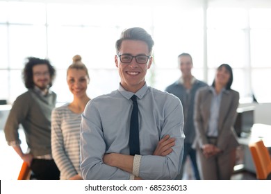 Portrait of smiling young casuall businessman with colleagues in background at the office - Shutterstock ID 685236013