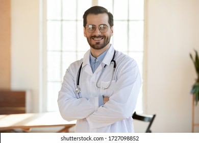 Portrait of smiling young caucasian male doctor wear white medical uniform, stethoscope and glasses look at camera posing in private clinic, happy man GP or show confidence at workplace in hospital
