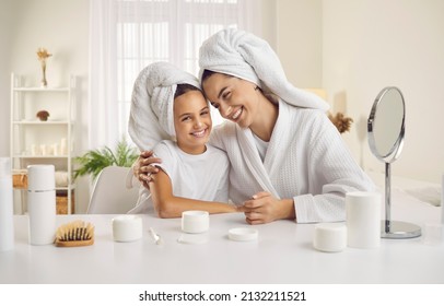 Portrait of smiling young Caucasian mother and teen daughter in bathrobes have fun do beauty procedures at home together. Happy mom and small girl child relax enjoy spa day. Cosmetology concept.