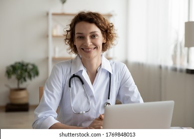 Portrait of smiling young Caucasian woman nurse sit at desk in hospital or private clinic, profile picture of happy positive female doctor GP in white medical uniform at workplace, healthcare concept - Powered by Shutterstock