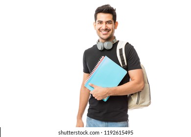 Портрет улыбающегося молодого студента колледжа с книгами и рюкзаком на белом фоне