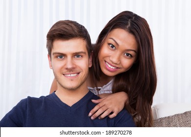 Portrait of smiling young couple in living room at home